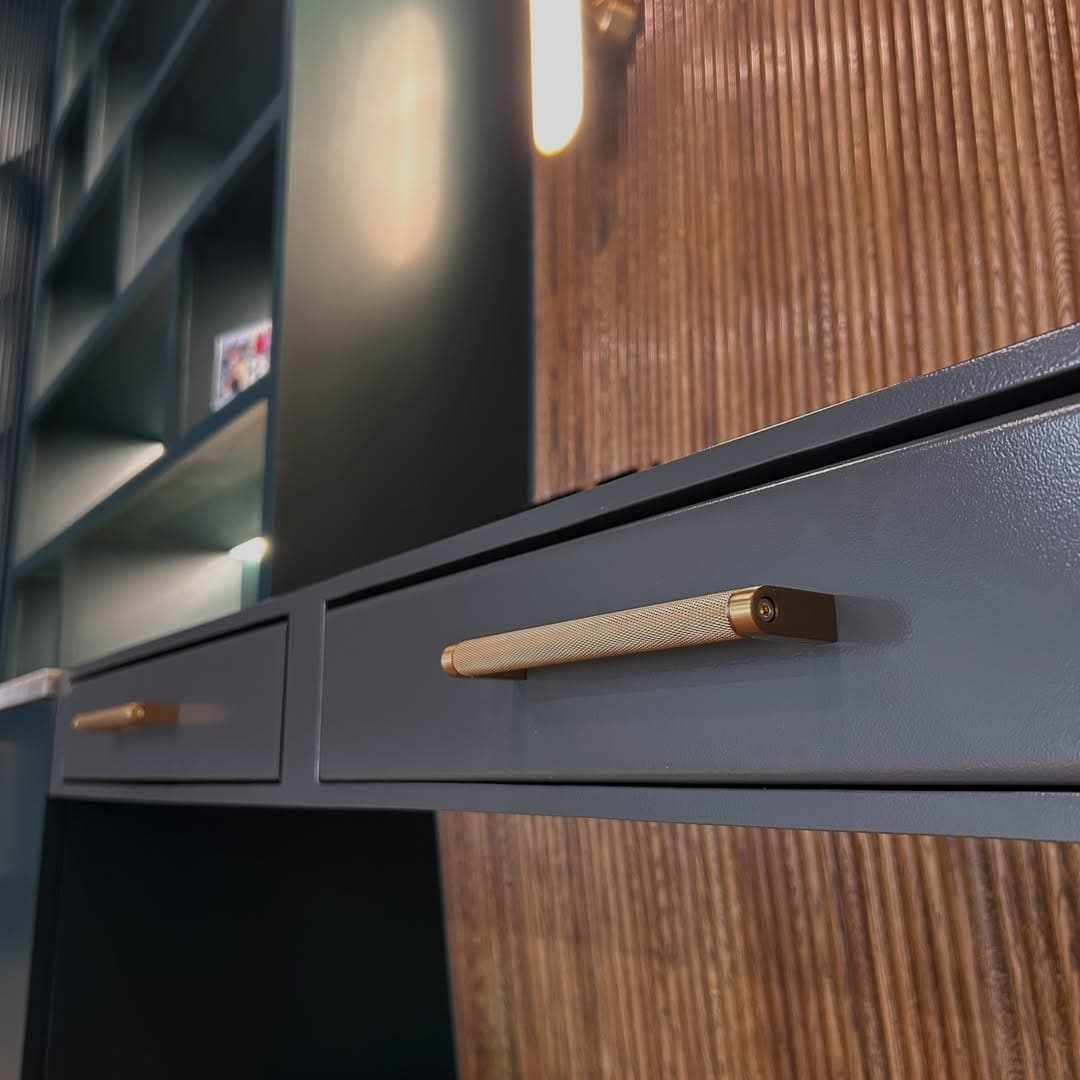 Detail of a blackened steel desk with knurled brass hardware
